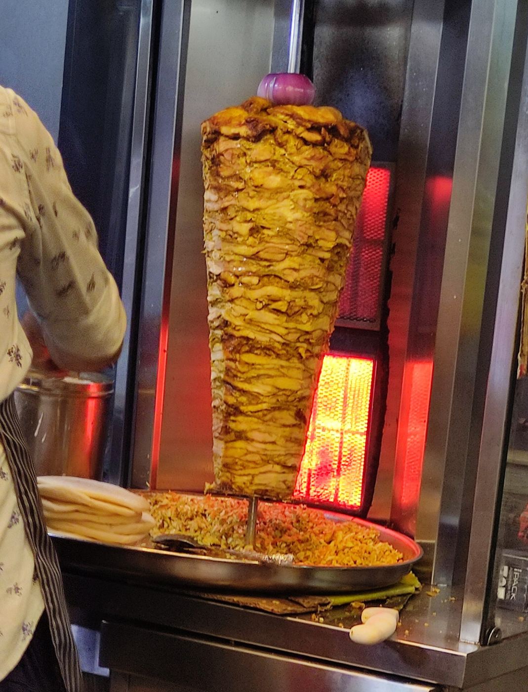 A shawarma wrap being prepared, sliced from a vertical spit