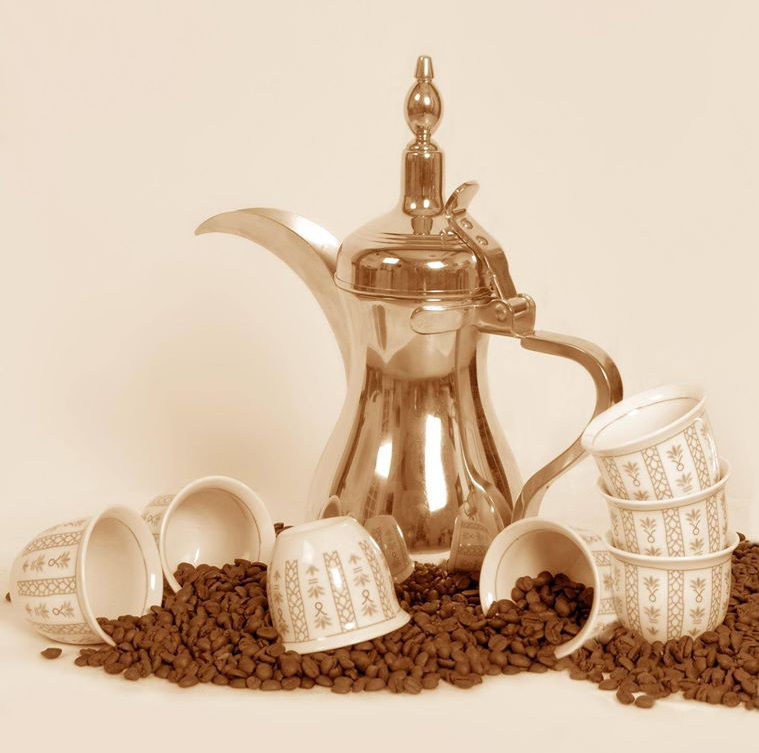 A traditional dallah coffee pot with small cups and coffee beans