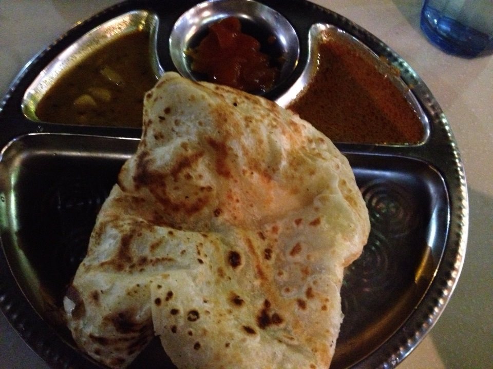 Roti canai being served with curry dipping sauce