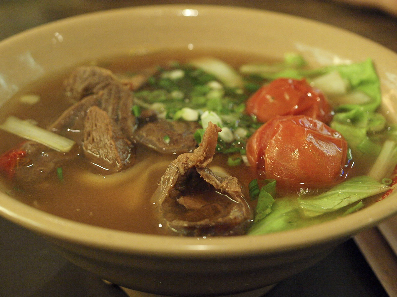 A bowl of Taiwanese beef noodle soup with tomato and beef