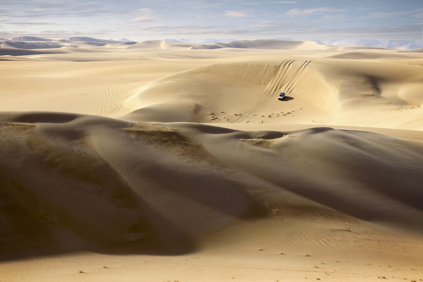 A 4x4 vehicle driving through the desert dunes near Doha