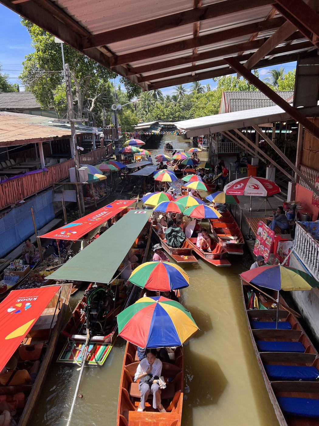 Vendors selling food from wooden boats at Damnoen Saduak Floating Market near Bangkok