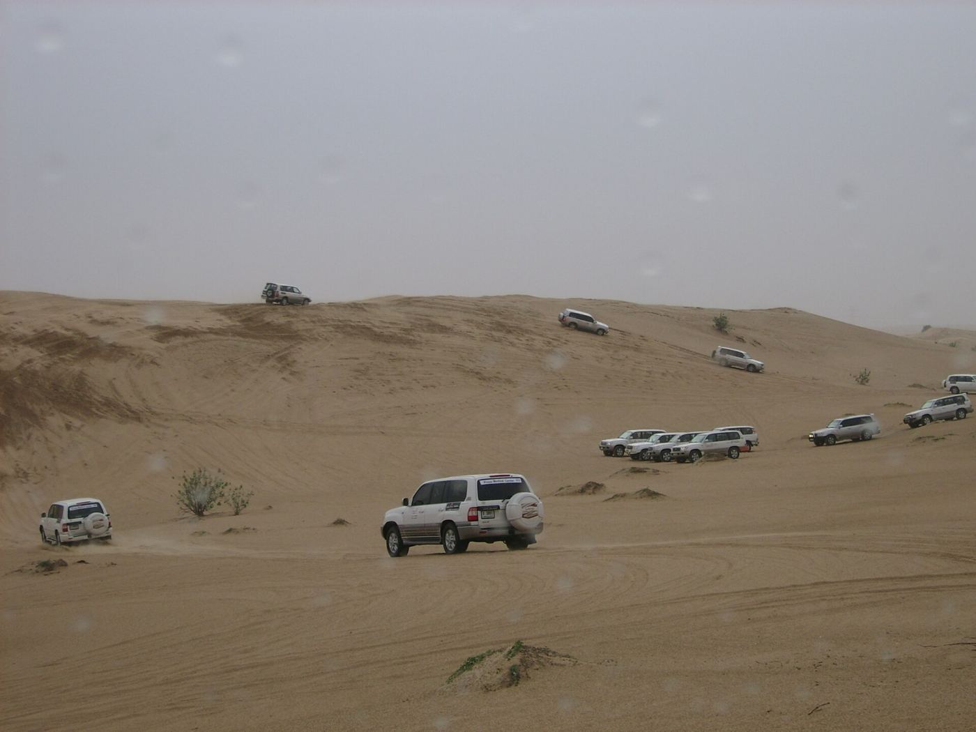 A convoy of 4x4 vehicles dune bashing on red sand dunes outside Dubai