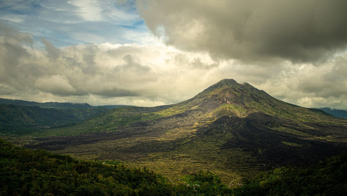 Mount Batur volcano in Bali surrounded by clouds and lava fields
