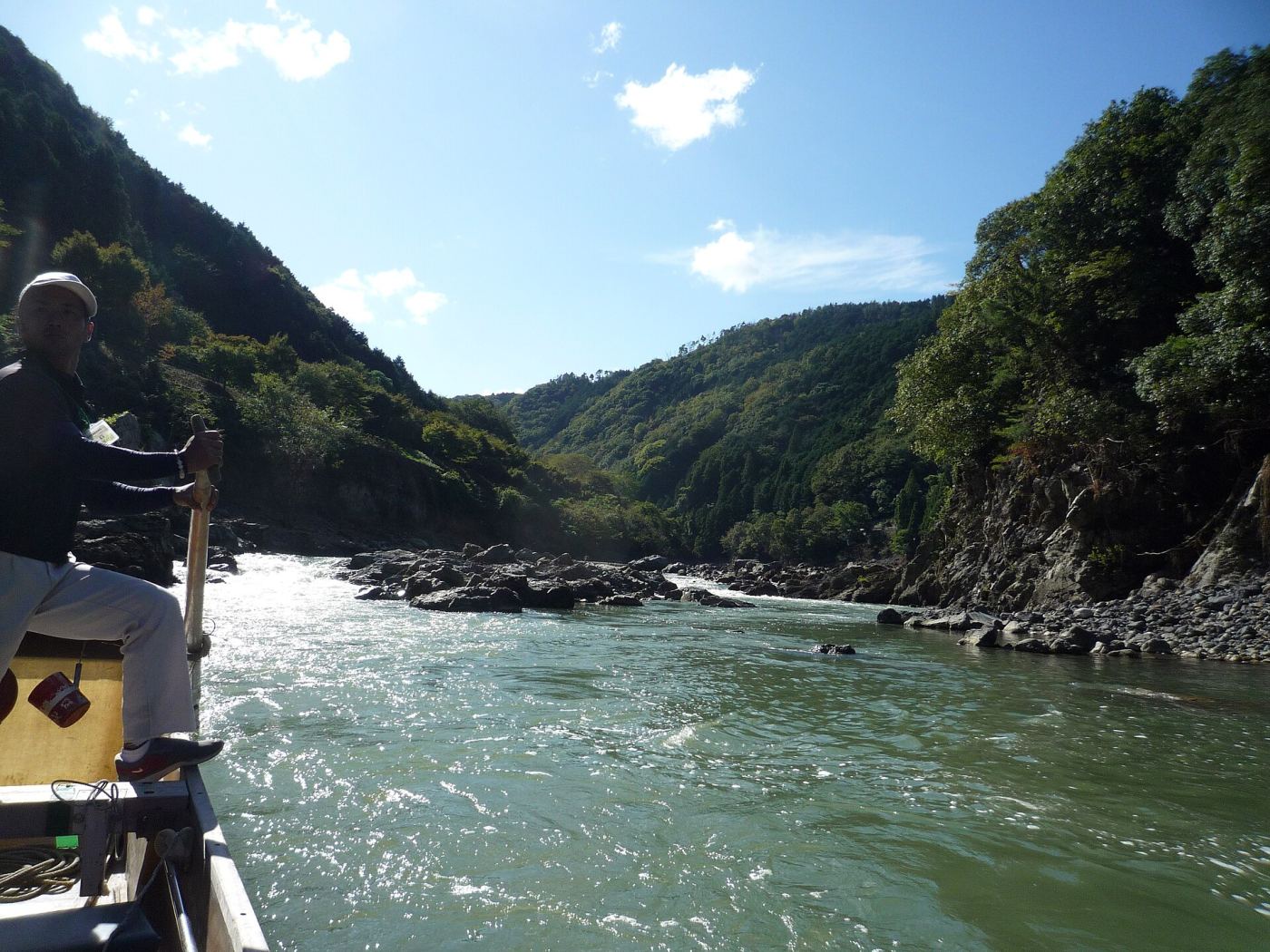 A boatman steering a traditional wooden boat down the Hozugawa River gorge near Arashiyama