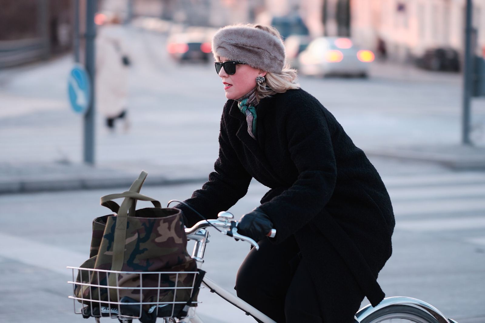 A cyclist riding through a Nordic city street in cold-weather clothing