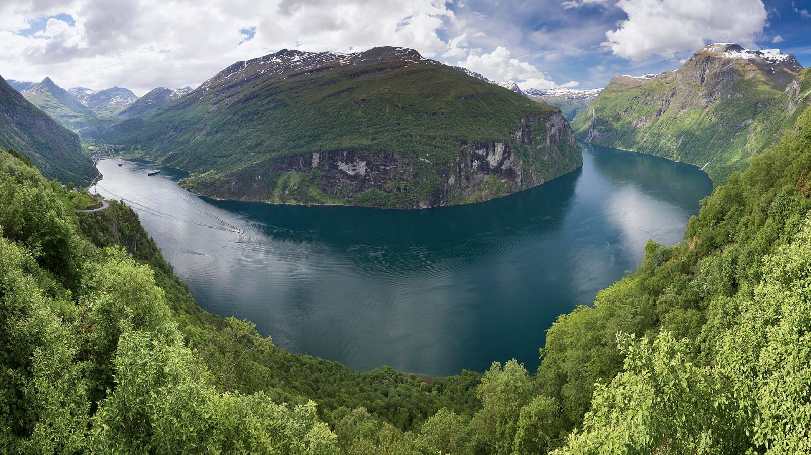 A dramatic Norwegian fjord with steep green mountains rising from deep blue water