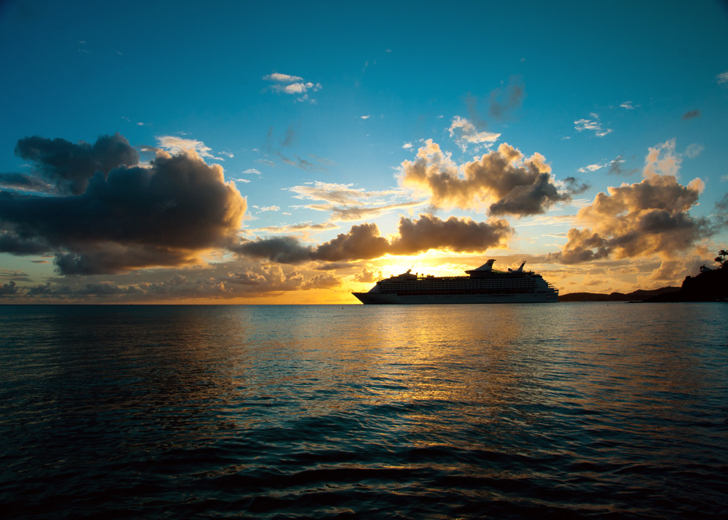 A ship silhouetted against a golden sunset over calm water