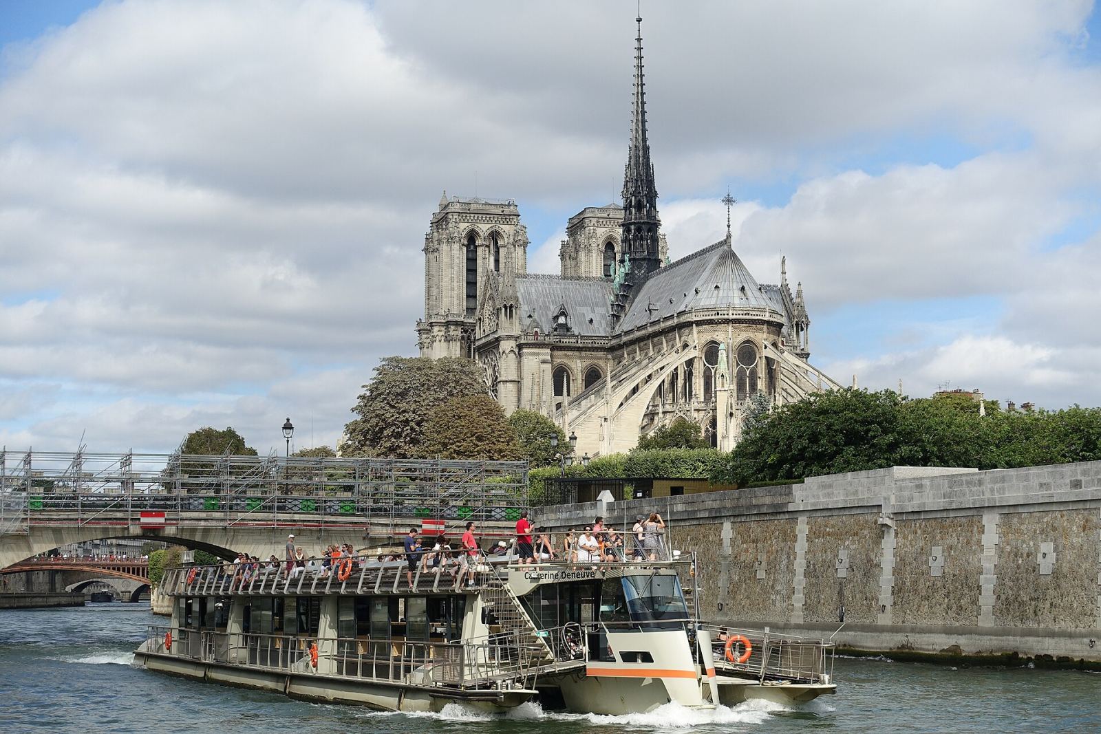 A Seine river tour boat passing in front of Notre-Dame Cathedral in Paris