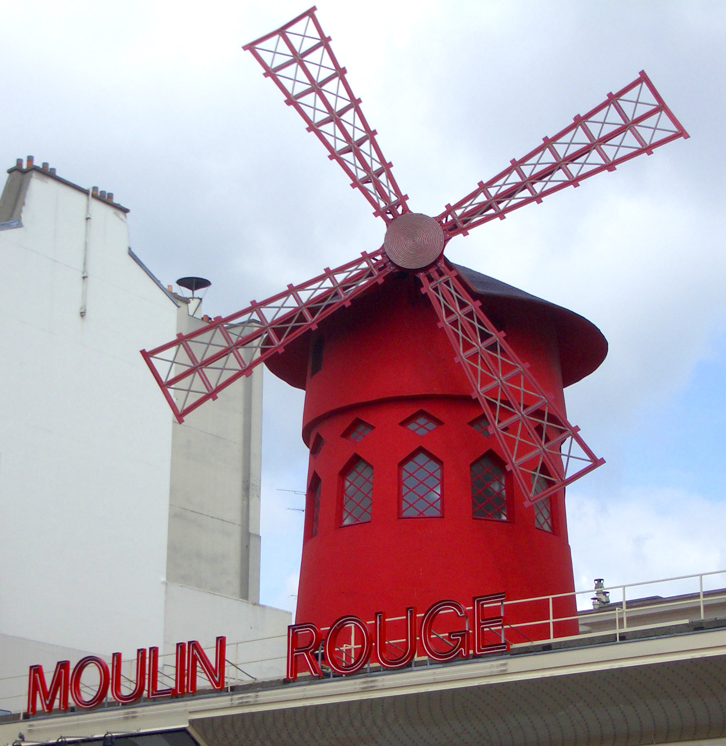The iconic red windmill and neon sign atop the Moulin Rouge cabaret venue in Paris