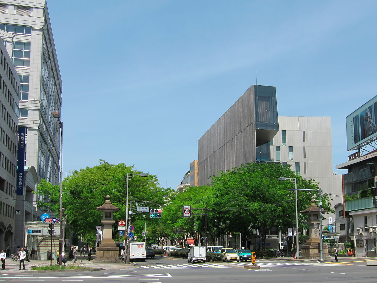 A wide tree-lined avenue intersection in the Omotesando and Aoyama area of Tokyo with modern architecture and greenery