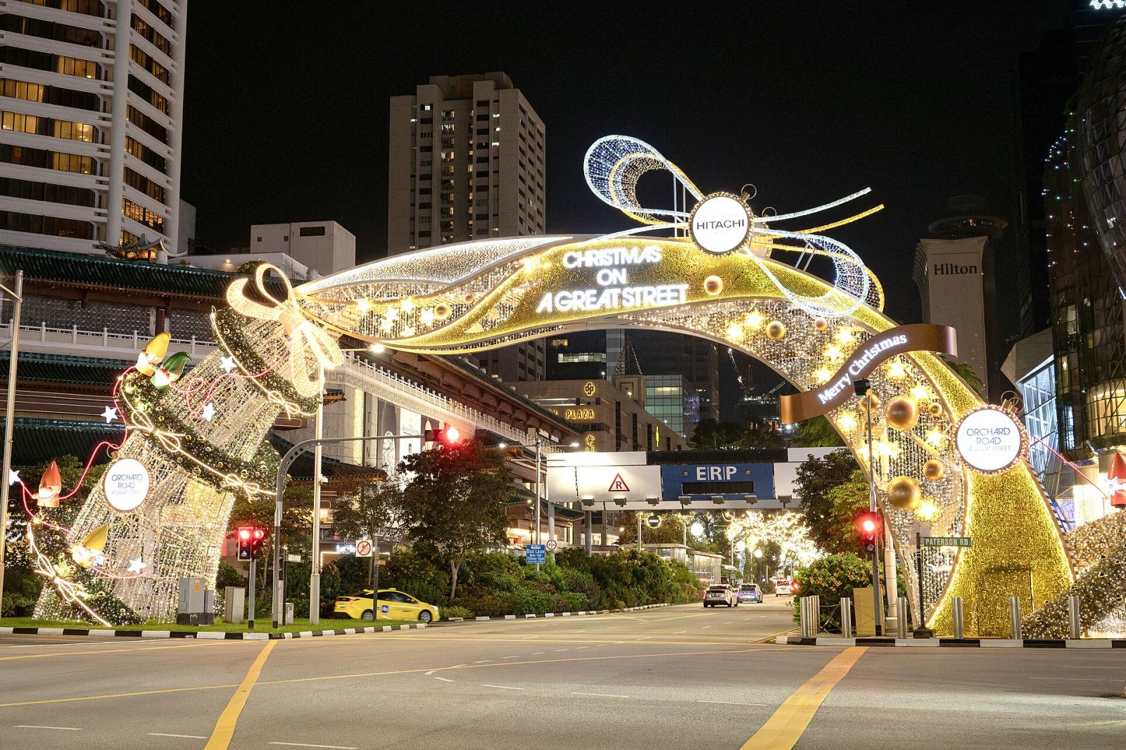 An illuminated golden Christmas archway reading 'Christmas on a Great Street' spanning Orchard Road in Singapore at night