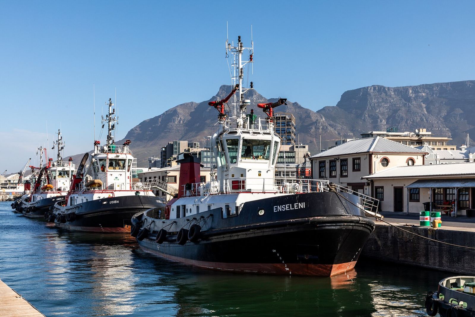 Tugboats docked at the V&A Waterfront harbor with Table Mountain behind them