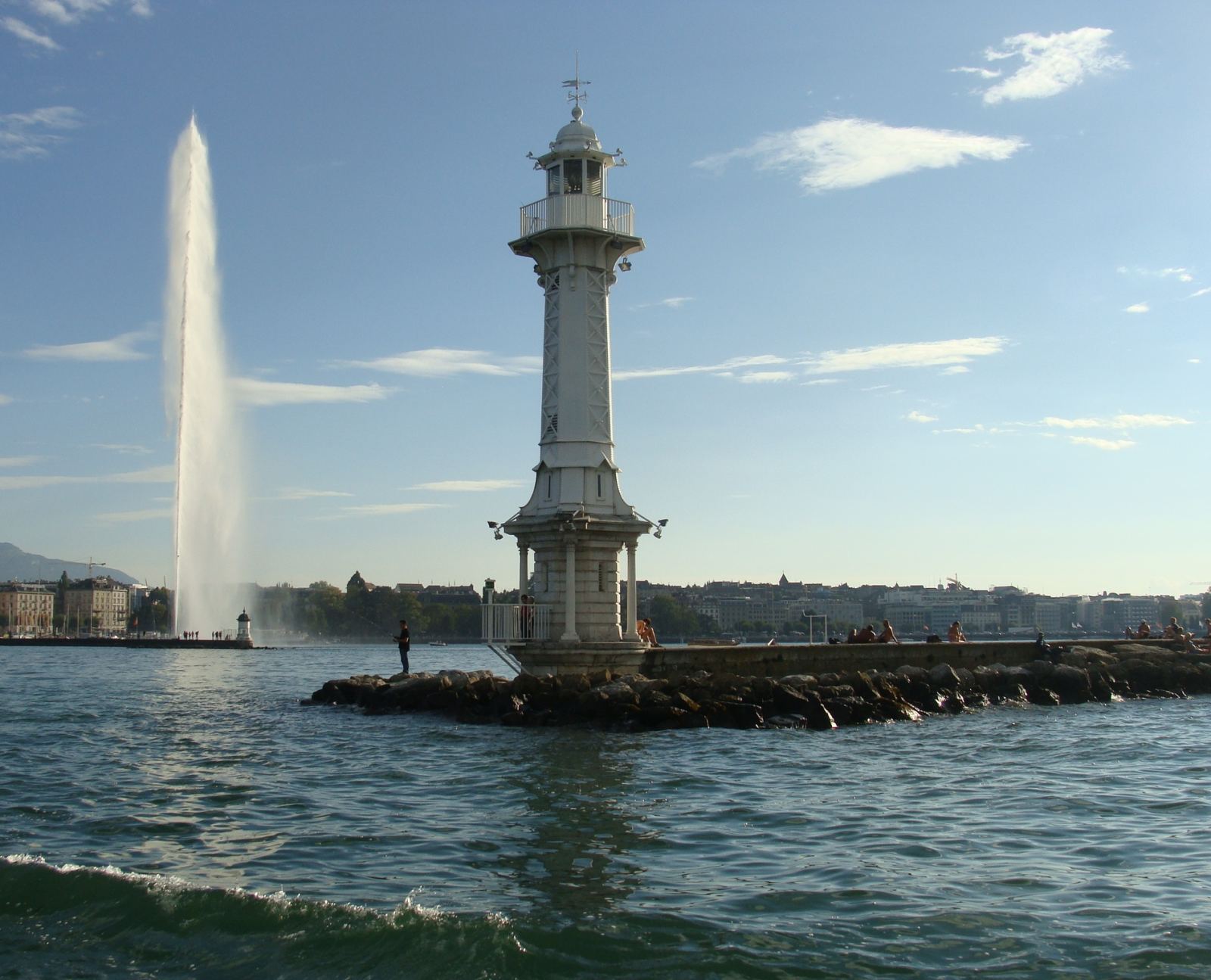 Pâquis lighthouse on Lake Geneva with the Jet d'Eau fountain in the distance