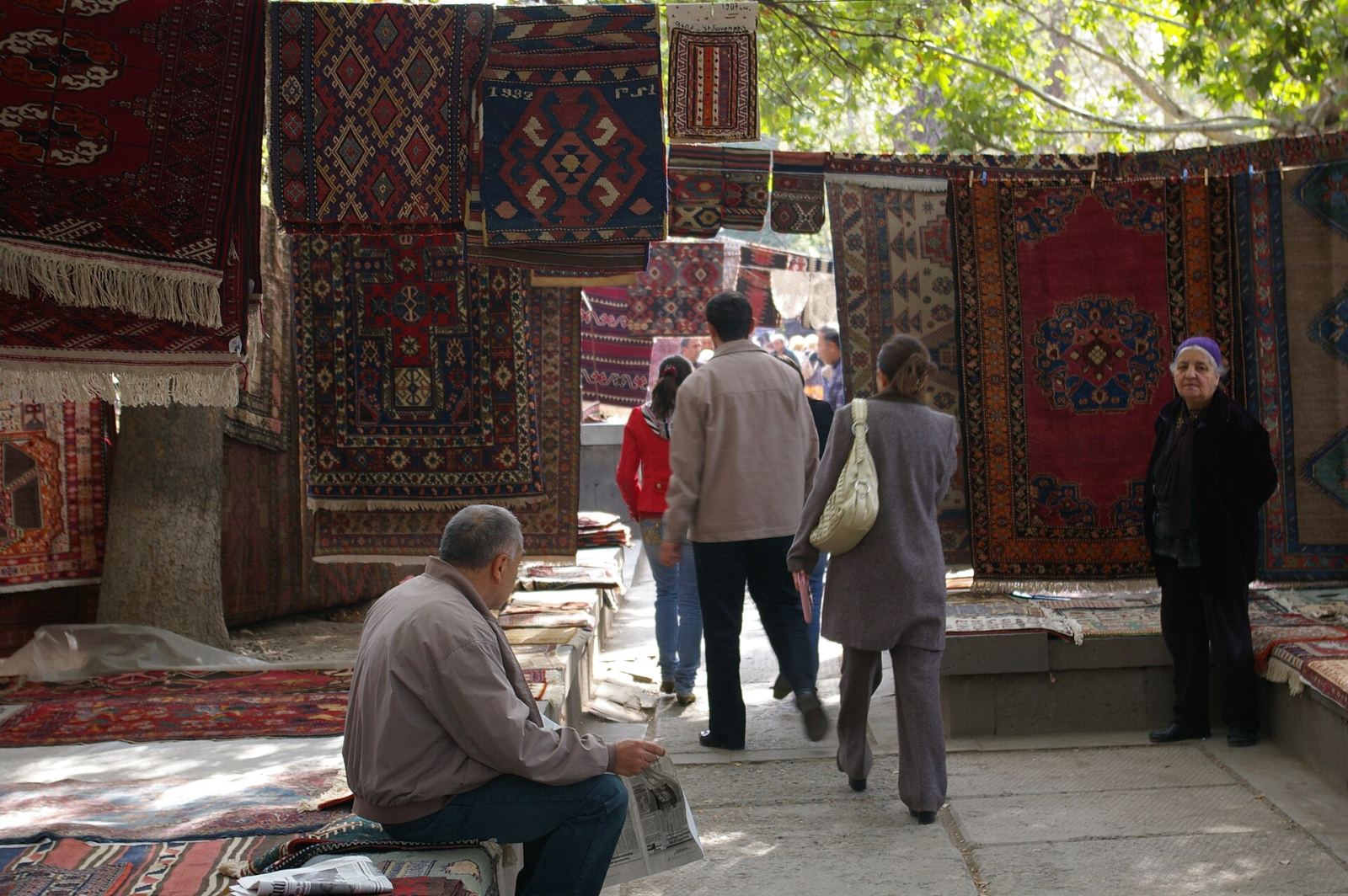 Shoppers browsing Vernissage Market rugs in Yerevan